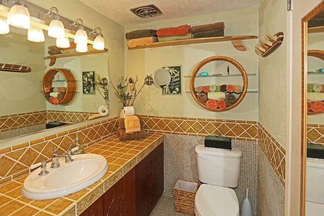 bathroom with vanity, tile walls, and toilet