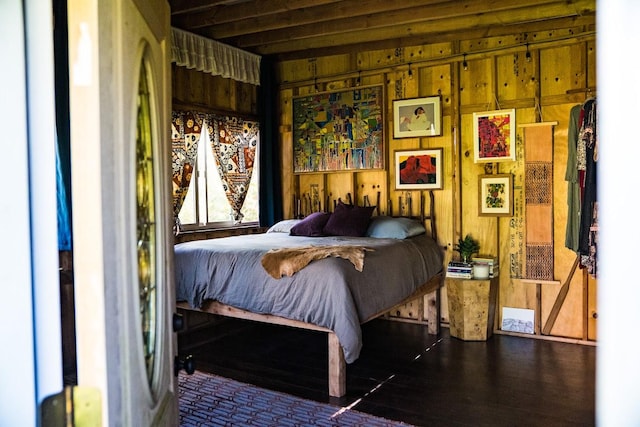 bedroom with dark hardwood / wood-style flooring and wood walls