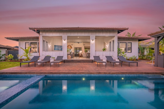 back house at dusk with ceiling fan and a patio area