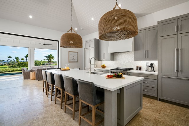 kitchen featuring pendant lighting, a center island with sink, sink, gray cabinets, and tasteful backsplash