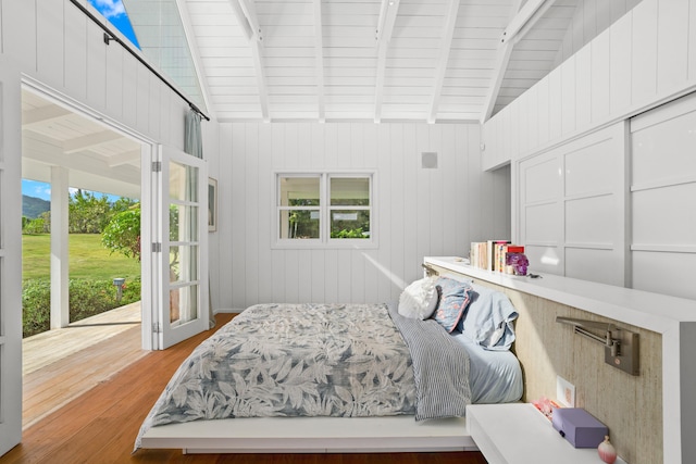 bedroom featuring wooden walls, hardwood / wood-style floors, and lofted ceiling with beams