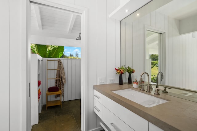 bar with beam ceiling, white cabinetry, sink, and wood walls