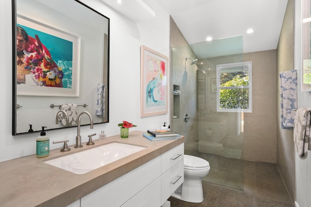 bathroom featuring a tile shower, vanity, and toilet