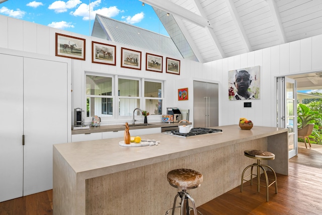 kitchen featuring a breakfast bar, sink, beam ceiling, wood-type flooring, and white cabinets