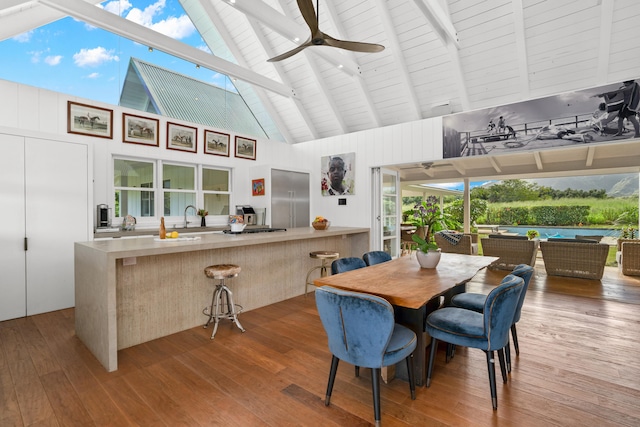 dining room featuring ceiling fan, beam ceiling, wood-type flooring, and high vaulted ceiling