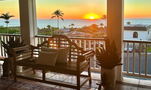 balcony at dusk featuring a water view