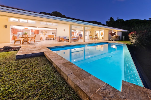 pool at night with a patio and an outdoor hangout area