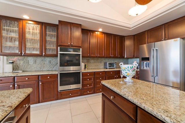 kitchen featuring backsplash, light stone countertops, stainless steel appliances, and light tile patterned floors