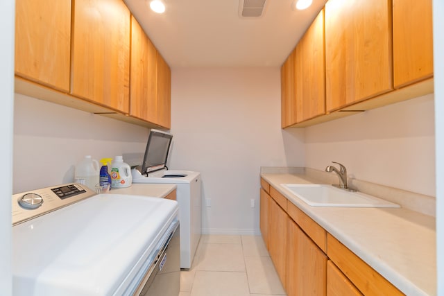 clothes washing area featuring light tile patterned flooring, washing machine and dryer, cabinets, and sink