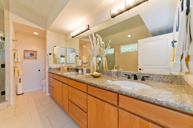 bathroom with toilet, vanity, tile patterned floors, and a shower with shower door