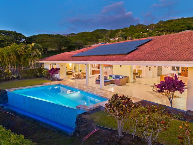 pool at dusk featuring outdoor lounge area and a patio