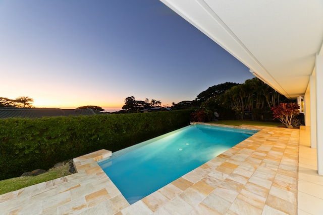 pool at dusk featuring a patio area