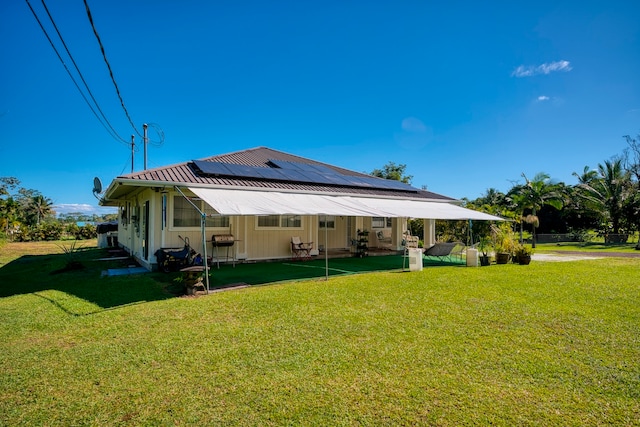 back of property with a lawn and solar panels