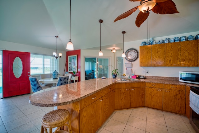 kitchen with a breakfast bar, lofted ceiling, sink, hanging light fixtures, and light tile patterned flooring