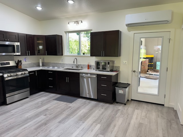 kitchen with sink, light hardwood / wood-style flooring, a wall mounted air conditioner, and appliances with stainless steel finishes