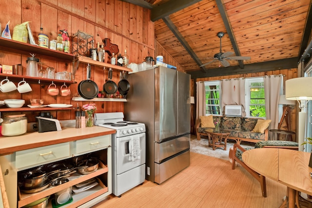 kitchen featuring white range, ceiling fan, lofted ceiling with beams, stainless steel refrigerator, and wood walls