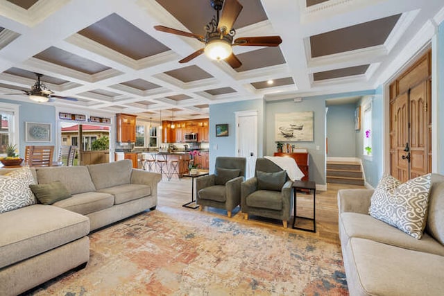 living room featuring ceiling fan, beamed ceiling, coffered ceiling, and ornamental molding