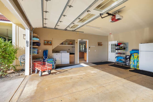 garage with washer and clothes dryer, white refrigerator, and a garage door opener