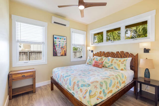 bedroom with a wall unit AC, ceiling fan, and hardwood / wood-style flooring