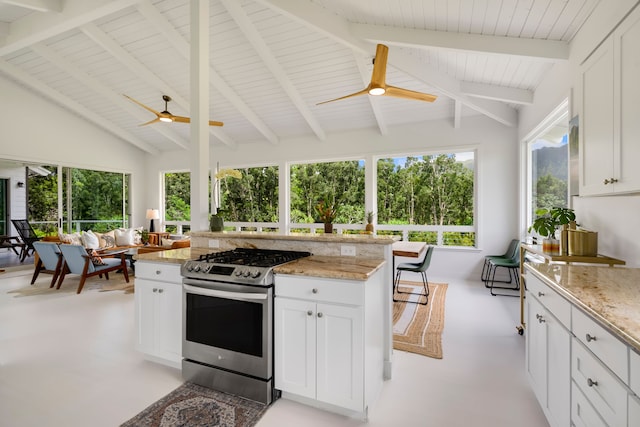 kitchen with gas stove, light stone counters, a healthy amount of sunlight, and white cabinetry