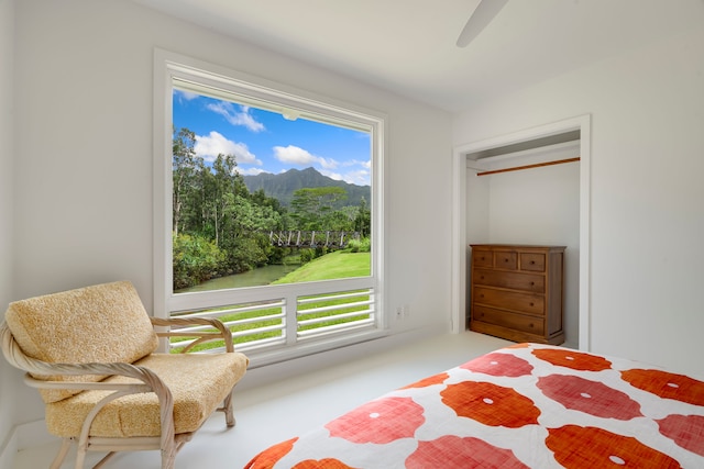 carpeted bedroom featuring multiple windows, ceiling fan, and a mountain view