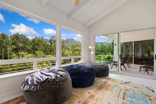 sunroom / solarium featuring lofted ceiling with beams, ceiling fan, and a mountain view