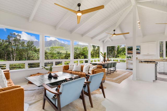 sunroom / solarium with vaulted ceiling with beams, a mountain view, and ceiling fan