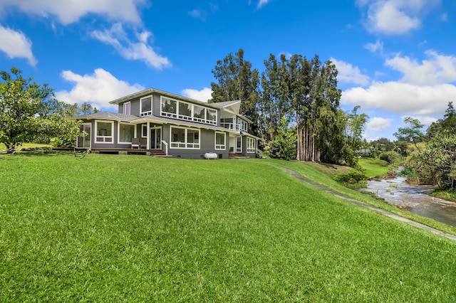 rear view of house featuring a yard and a sunroom