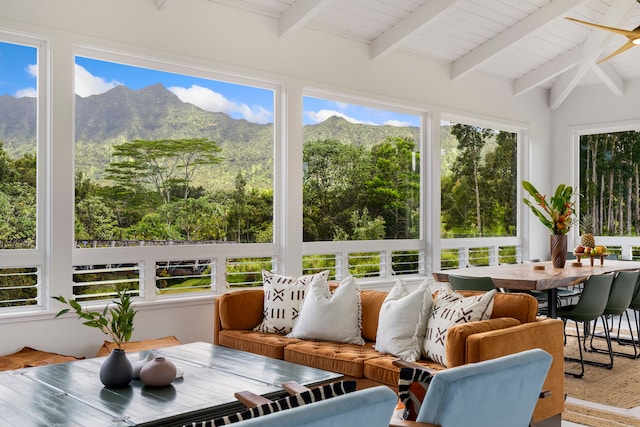 sunroom featuring a mountain view, vaulted ceiling with beams, and a healthy amount of sunlight