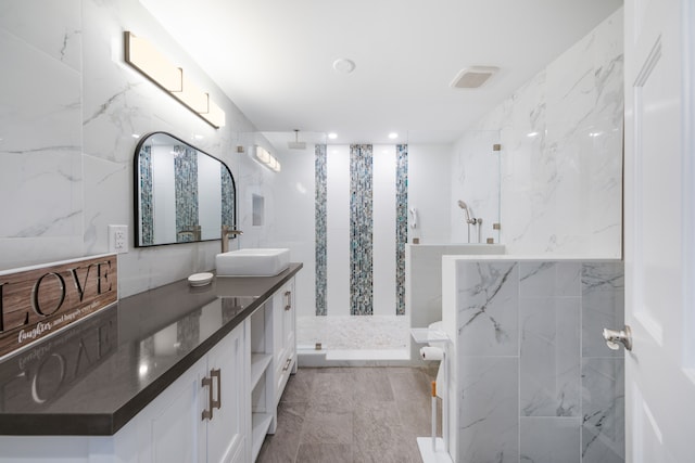 bathroom with vanity, a tile shower, and tile walls