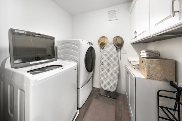 laundry room featuring cabinets, washing machine and dryer, and dark hardwood / wood-style floors