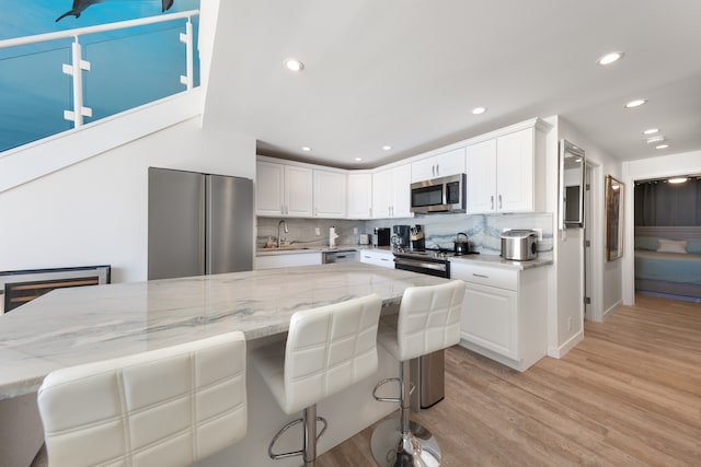 kitchen featuring white cabinets, a kitchen breakfast bar, backsplash, and stainless steel appliances