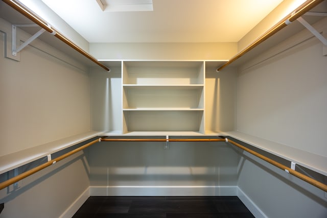 walk in closet with dark wood-type flooring