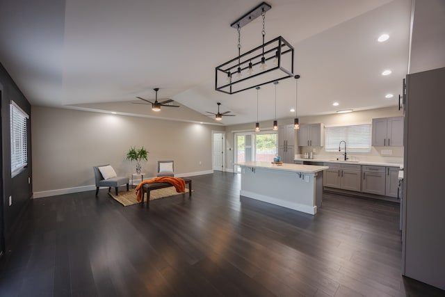 kitchen with dark hardwood / wood-style floors, a center island, sink, and hanging light fixtures