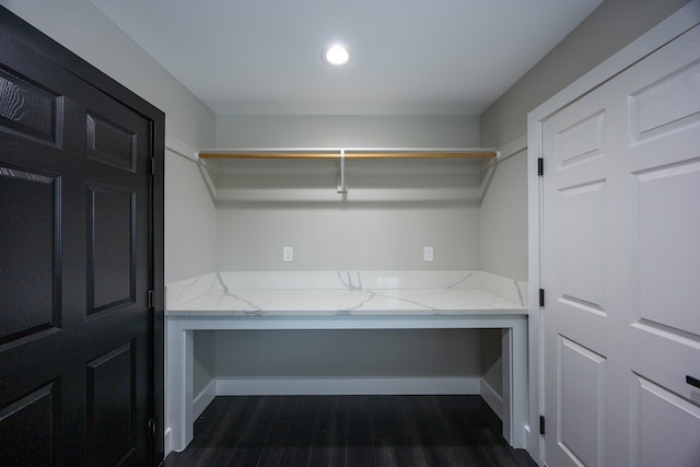 spacious closet with dark hardwood / wood-style floors and built in desk