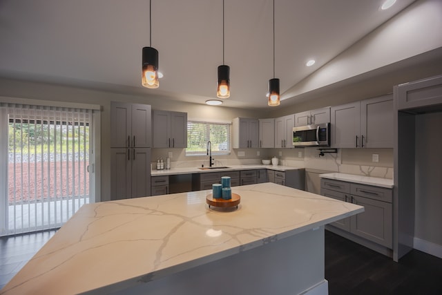 kitchen with gray cabinets, light stone countertops, decorative light fixtures, and vaulted ceiling