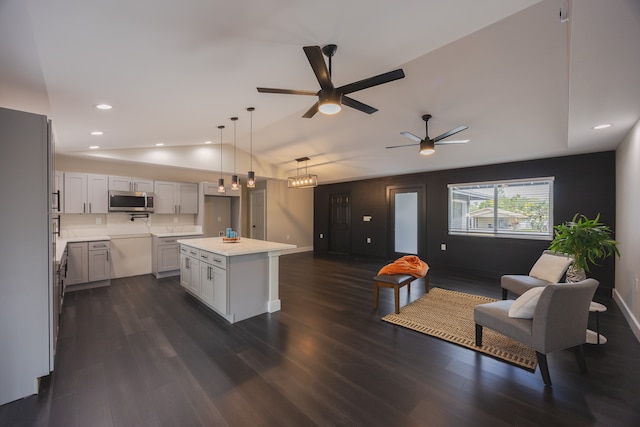 kitchen with vaulted ceiling, ceiling fan, decorative light fixtures, a center island, and dark hardwood / wood-style floors