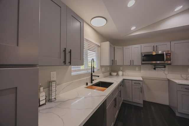 kitchen with light stone countertops, dark hardwood / wood-style flooring, gray cabinetry, sink, and lofted ceiling