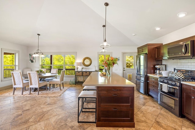 kitchen with pendant lighting, a kitchen island, stainless steel appliances, and tasteful backsplash