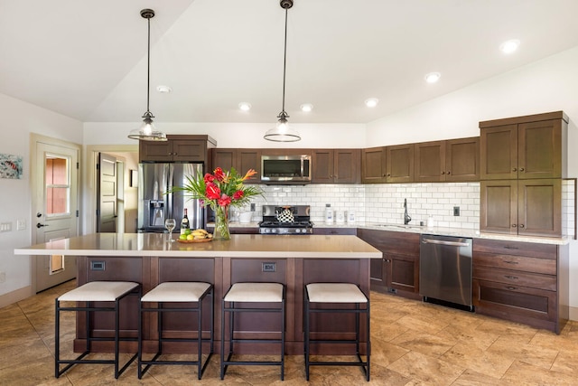 kitchen with hanging light fixtures, a kitchen breakfast bar, an island with sink, and appliances with stainless steel finishes