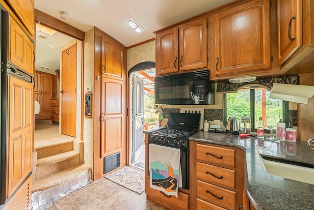 kitchen with gas stove, dark stone countertops, and sink