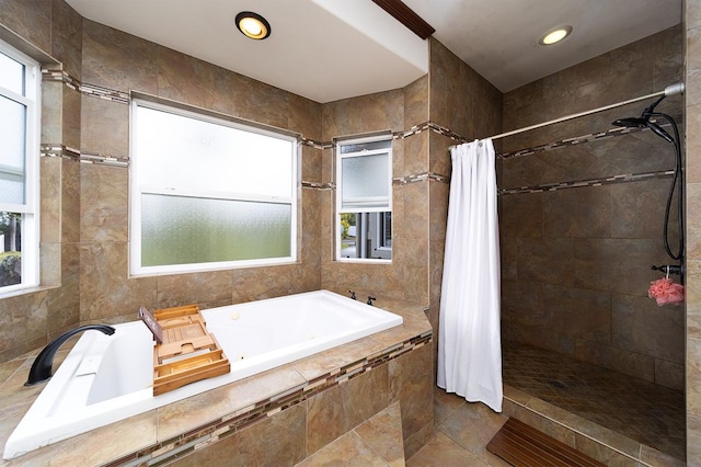 bathroom with tile patterned flooring, shower with separate bathtub, and tile walls