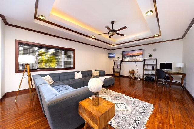 living room with ornamental molding, a raised ceiling, ceiling fan, and dark wood-type flooring