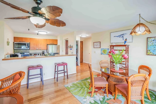 dining area with ceiling fan and light hardwood / wood-style flooring