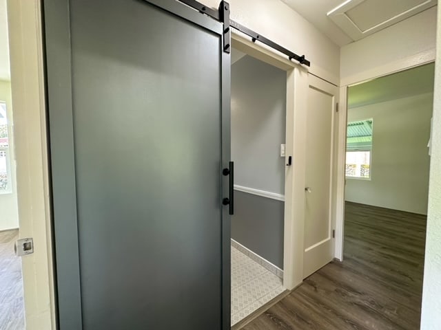 hallway with a barn door and dark hardwood / wood-style flooring