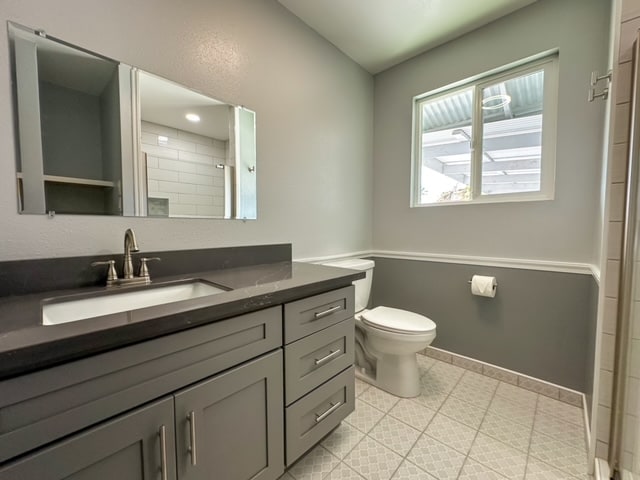 bathroom with a tile shower, vanity, and toilet