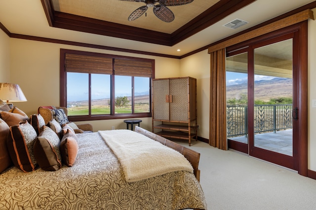 bedroom featuring a mountain view, access to outside, ceiling fan, a tray ceiling, and light colored carpet