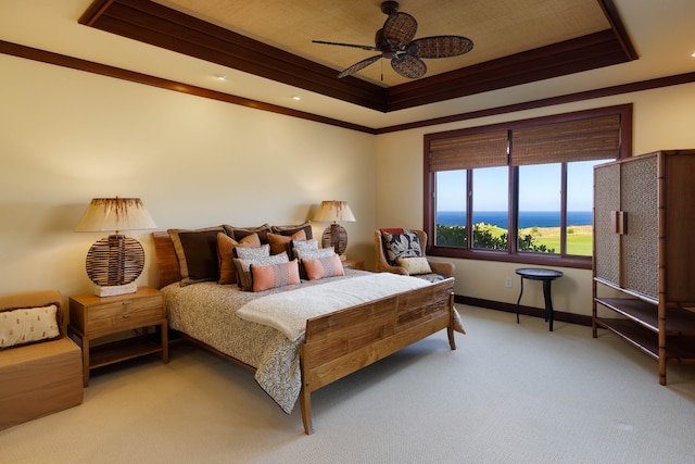 carpeted bedroom with a tray ceiling, ceiling fan, and crown molding