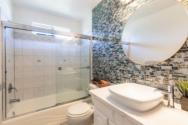 full bathroom featuring tile walls, bath / shower combo with glass door, tasteful backsplash, vanity, and toilet