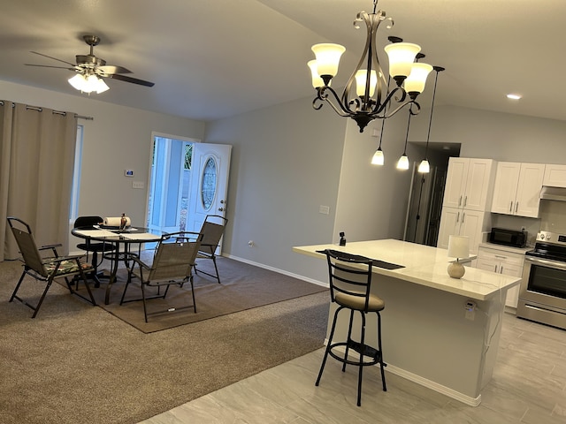 kitchen with hanging light fixtures, a kitchen island, stainless steel electric range, white cabinets, and ceiling fan with notable chandelier